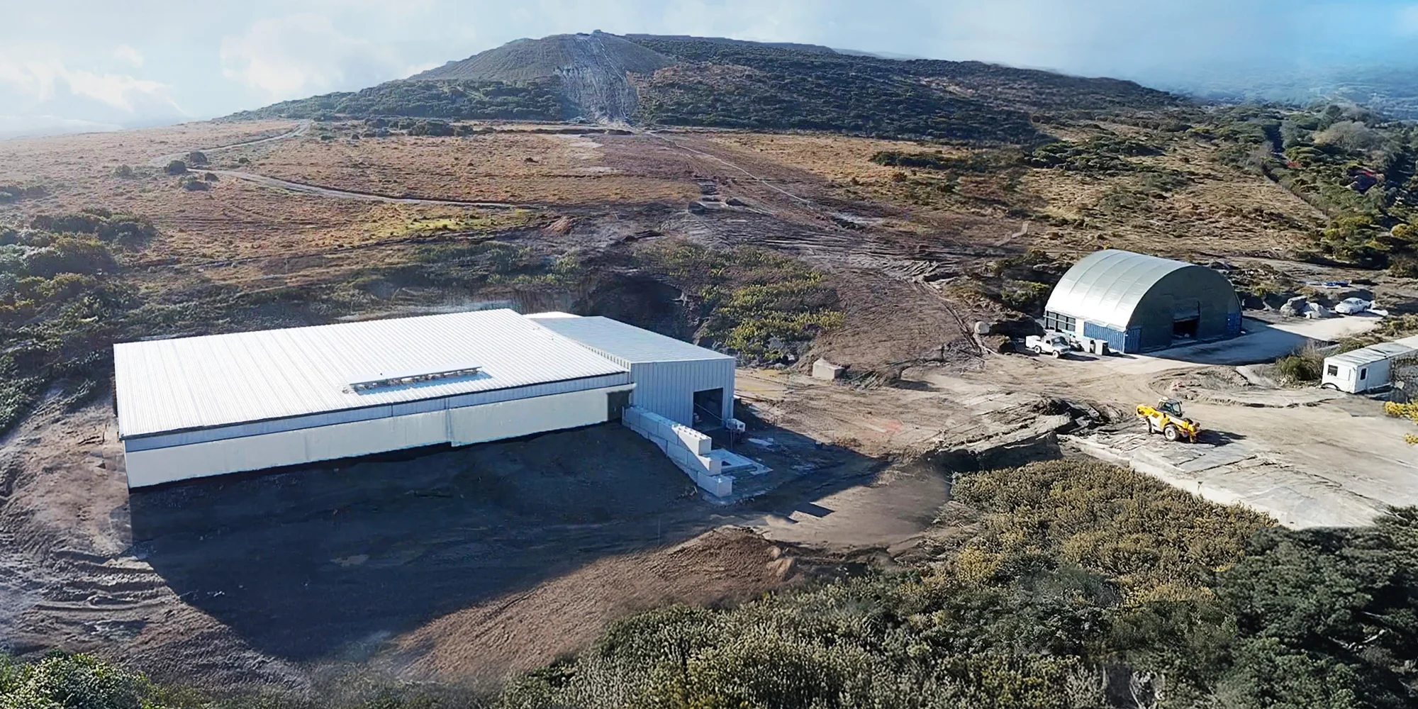 The building on the left contains the lower reservoir and power house; and the upper reservoir is buried on the hillside in the distance. The domed building on the right is the temporary fluid-mixing shed.